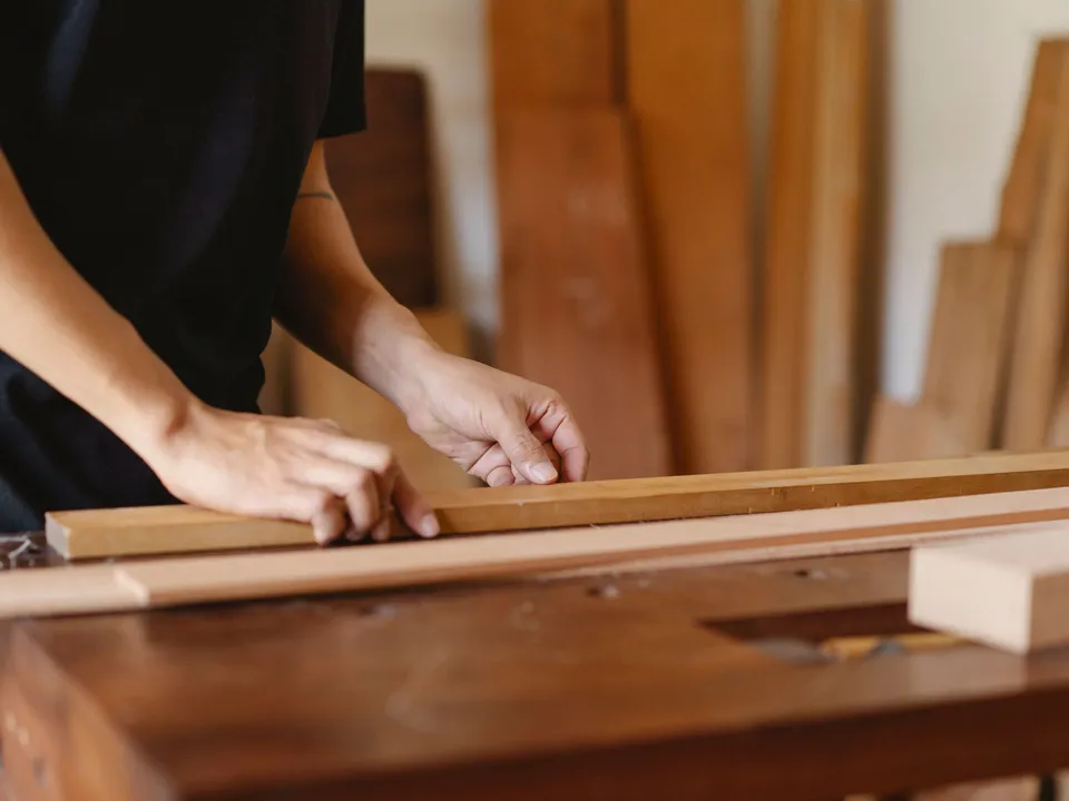 A carpenter measuring and marking a length of timber