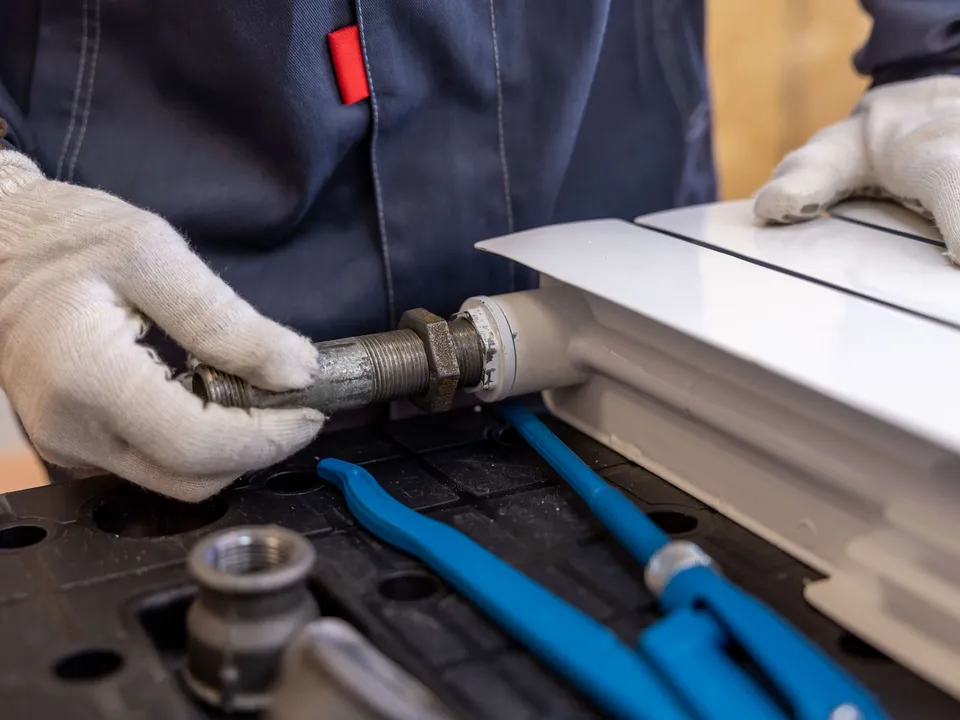 A plumber fitting a radiator pipe with a spanner